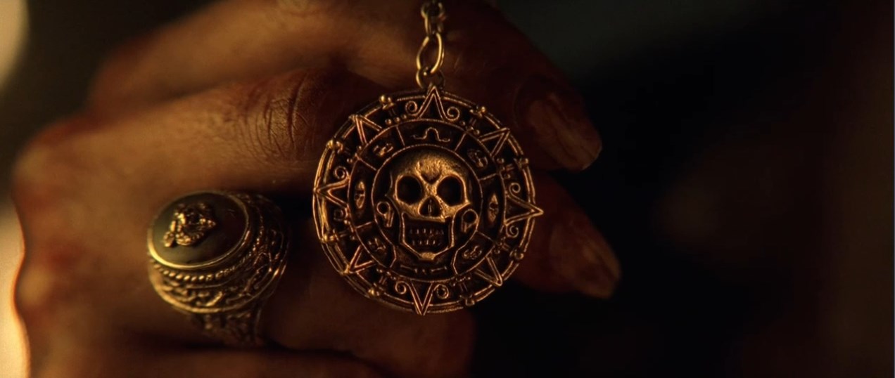 — Вы не знаете, что это такое? Верно?
— Пиратский медальон.
— Это ацтекское золото, одна из шестисот шестидесяти трёх бляшек, что индейцы отнесли Кортесу как выкуп... выкуп за кровь, доставленный с надеждой положить конец расправам. Но алчность Кортеса была неутолима, и тогда языческие боги придумали страшное проклятие. Любой из смертных, кто возьмёт хоть одну золотую бляшку, обречён на вечные муки.