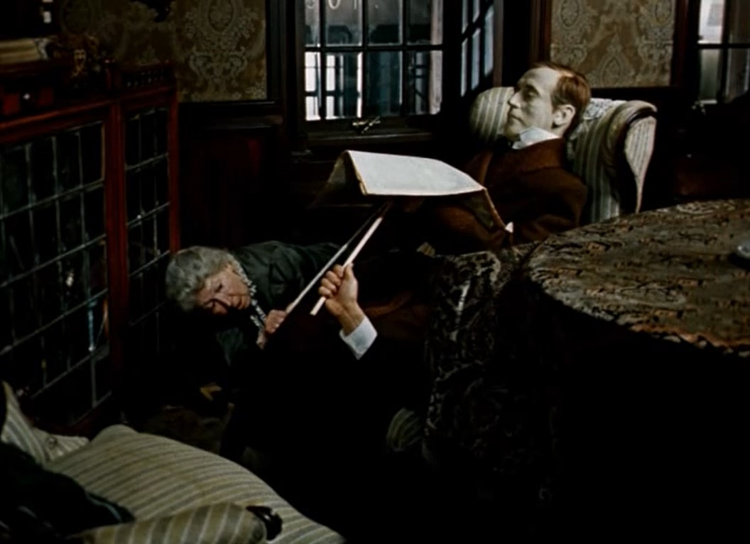 [Ватсон видит воскового Холмса в окне их дома напротив]
— Неплохо придумано, правда?
— Что это?
— Произведение искусства. Работа скульптора Менье из Гренобля. Он делал эту восковую фигуру две недели.
— Зачем?
— Чтобы они думали, что я там, в то время, как я здесь.
— Кто?..
— Вы что забыли, что за нашим домом следят?
— Кто?..
— Очаровательная компания, глава которой покоится на дне Рейхенбахского водопада.
— Смотрите, он... живой...
— Ну разумеется...
[сцена Майкрофта и Хадсон, которые ползают под столом и двигают восковую фигуру]